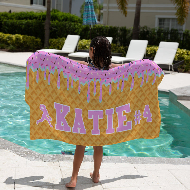 Ice Cream Drip Softball Personalized Beach Towel - Pink/Blue with a girl holding the towel next to a pool